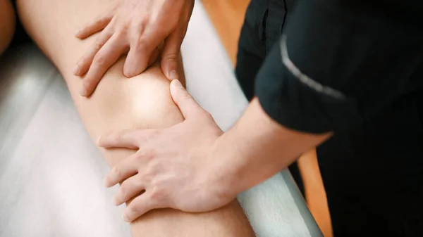Fisioterapeuta verificando seus pacientes joelho — Fotografia de Stock