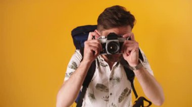 Sırt çantalı genç, heyecanlı turist klasik fotoğraf makinesiyle fotoğraf çekiyor. Yavaş çekim izole edildi