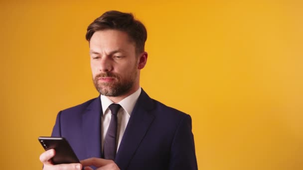 Задумчивый бизнесмен держит смартфон, пишет смс или читает слухи — стоковое видео