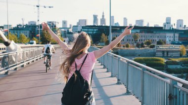 Sırt çantalı genç bir kadın. Özgürlük kavramı. Yükselen eller havaya. Yayalar yukarı, çekim devam.