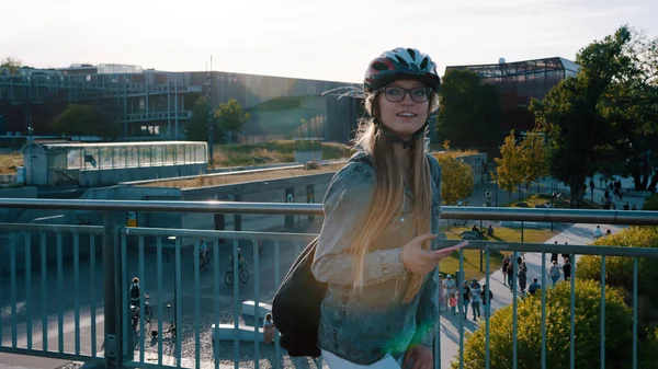 Retrato de una joven feliz patinando sobre el puente y usando un smartphone. — Foto de Stock