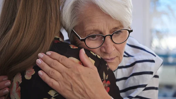 Een jonge vrouw die een oudere vrouw omarmt. Verdriet en kralen nieuws, empathie concept — Stockfoto