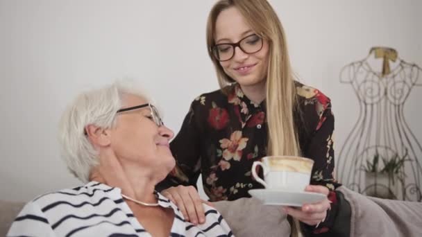 Νεαρή λευκή γυναίκα προσφέρει τσάι σε μια ηλικιωμένη κυρία. Αργή κίνηση — Αρχείο Βίντεο