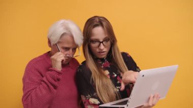 Genç bir kadın dizüstü bilgisayarda yaşlı bir bayana bir şey anlatıyor. Stüdyo çekimi