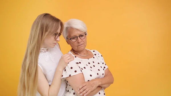 Young woman calming down senior lady after bad news. Family love and care concept