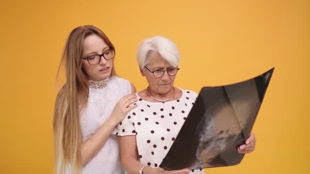 Dua perempuan khawatir, muda dan senior memegang x-ray o MRI kepala scan — Stok Video