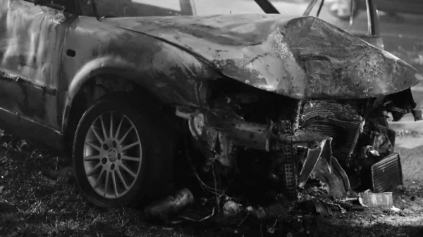 Front view of the car burned after the serious car accident at night in winter. Black and white