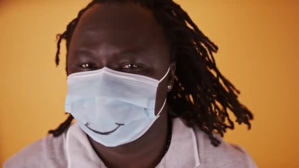 얼굴에 마스크를 쓴 아프리카 남자가 땋은 머리를 흔들고 있다 — 비디오