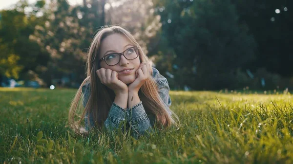 Een jonge blanke vrouw die een pauze heeft van haar werk of school in het park, ontspannen op het gras. Kopieerruimte — Stockfoto