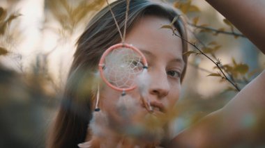 Hippi kadın rüya yakalayıcıdan bakıyor.