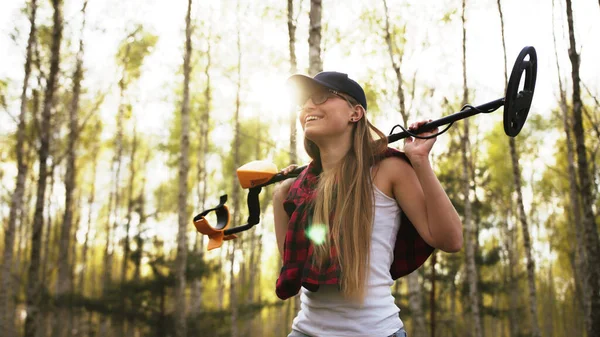 Een succesvolle zoektocht. Jonge vrouw met metaaldetector in het bos. Direct zonlicht — Stockfoto