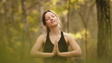 namaste yogasında oturan kadın ruhani rahatlama, huzur ve meditasyon içinde ormanda poz veriyor.