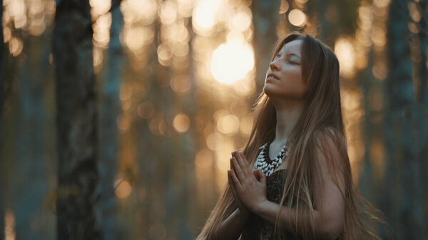 Female sorcerer in the woods. Prayer or magical ritual. High quality photo