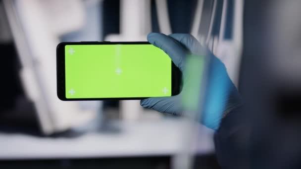 Fecha. Médico com luvas de látex médica segurando smartphone com tela verde. Chamada de vídeo durante pandemia — Vídeo de Stock