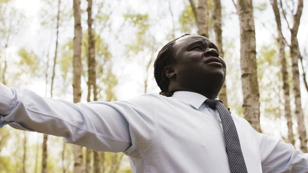 Siyahlar yaşıyor. Parkta dua eden ellerini uzatmış Afrikalı işadamı. — Stok fotoğraf