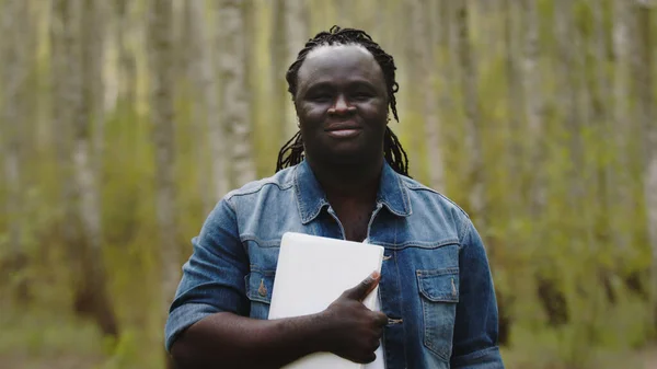 Porträtt av ung afrikansk man håller tablett i parken — Stockfoto