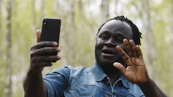 Afričan brát selfie nebo mít videokall na svém smartphonu v přírodě — Stock fotografie