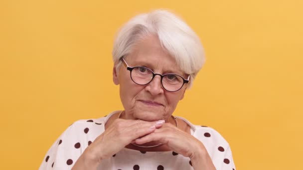 Grave donna anziana che poggia la testa sulle mani inizia a sorridere. Isolato sullo sfondo arancione — Video Stock