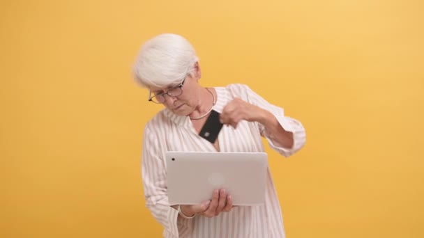 Senior kvinna försöker sätta in kreditkort i laptopen. Onlineshoppning — Stockvideo