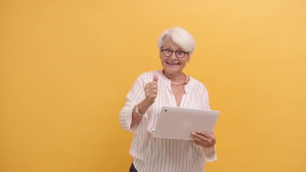 Uśmiechnięta szczęśliwa seniorka pokazująca kciuki do góry po obejrzeniu ekranu laptopa — Wideo stockowe