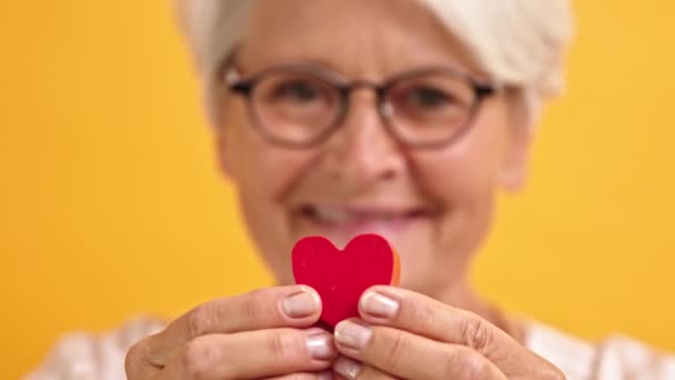 Sluit maar af. Gelukkige oudere vrouw die de hartvorm tussen haar vingers laat zien. Emotie liefde en ondersteuning concept — Stockvideo