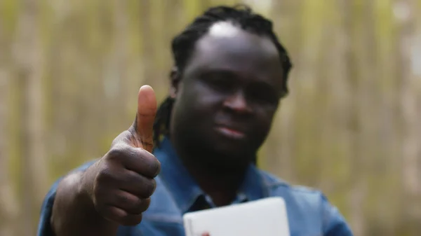 Parkta tabletli Afrikalı bir adam baş parmağını kaldırdı.. — Stok fotoğraf