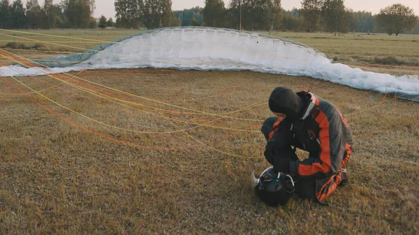 Parapente revisando su casco antes de deslizarse. Paracaídas en el fondo — Foto de Stock