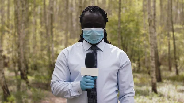 Africký reportér s obličejovou maskou a rukavicemi v lese, reportáž o šíření koronaviru — Stock fotografie