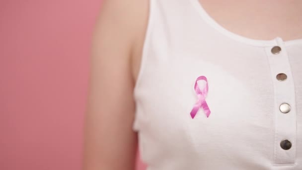 Símbolo del mes de conciencia sobre el cáncer de mama, insignia rosa de octubre en la camisa blanca de una mujer irreconocible — Vídeo de stock