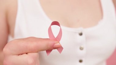 Yakından, elinde sembolik pembe kurdele olan kadın kanser farkındalığı konsepti.