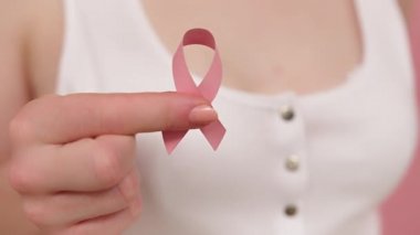 Yaklaş, elinde sembolik pembe kurdele, göğüs kanseri farkındalığı ve umut kavramı olan kadın.