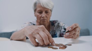 Endişeli, gri saçlı, bozuk para sayan bir kadın. Düşük emeklilik kavramı