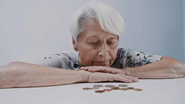 Triste expressão facial da velha mulher de cabelos grisalhos olhando em poucas moedas deixadas na mesa — Fotografia de Stock