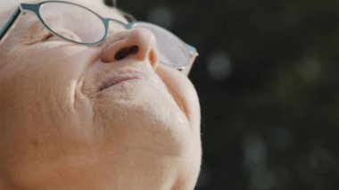 Yaşlı kadın, güneşli sonbahar gününde esintinin tadını çıkarırken baskıyla yüzleşir.