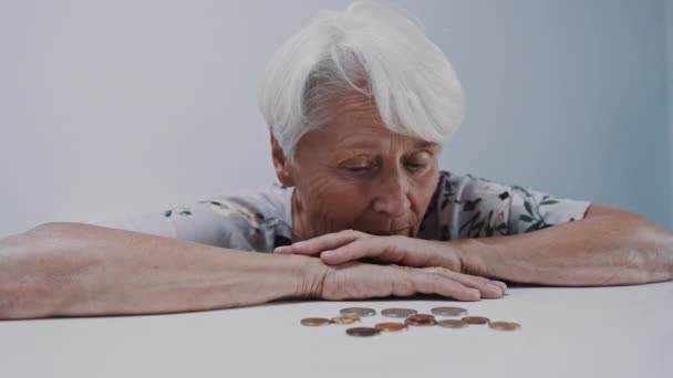 Triste expression de visage de vieille femme aux cheveux gris regardant dans quelques pièces de monnaie sur la table — Video