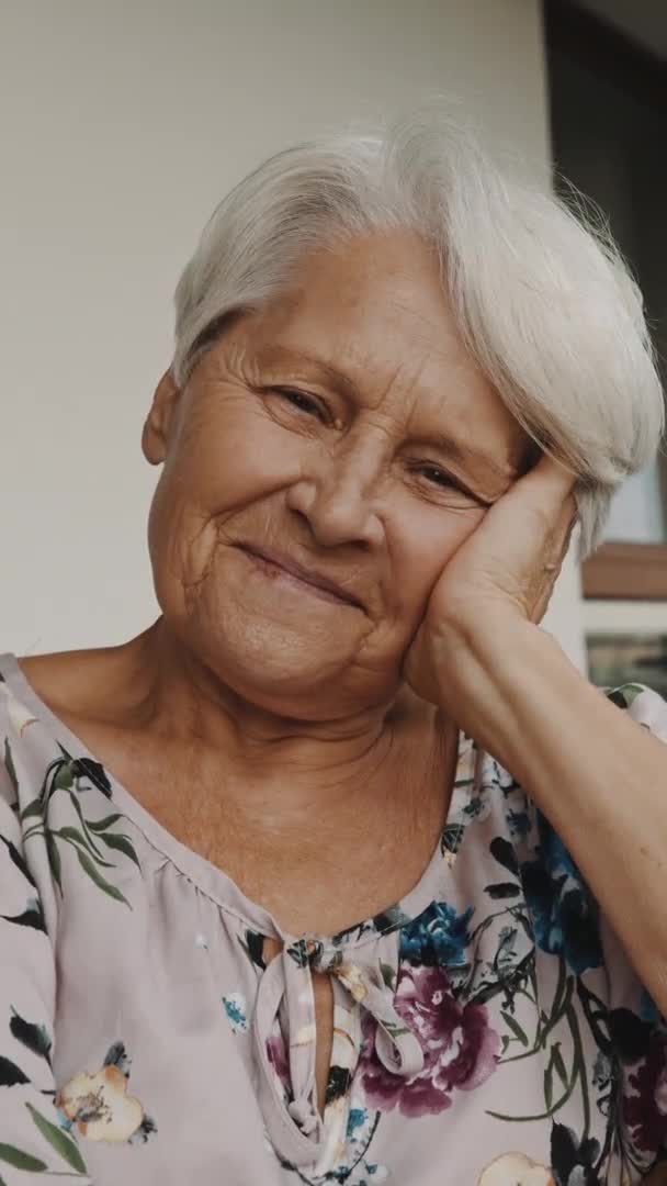 Verticaal. attente oudere vrouw met een glimlach die in de verte kijkt. Portret met kopieerruimte — Stockvideo