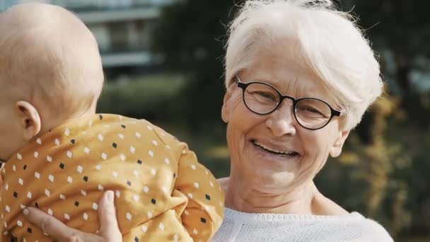 Feliz abuela sosteniendo a su nieto bebé en la naturaleza — Vídeos de Stock