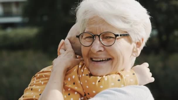 Close up, happy grandmother embracing her grandson in nature — Stock Video