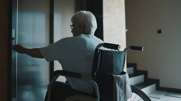 Пожилая женщина-инвалид вызывает лифт в больничном зале — стоковое фото