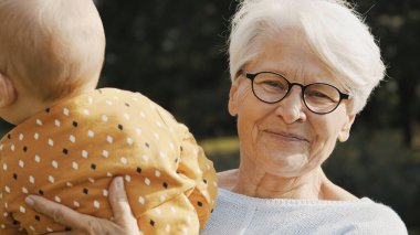 Torununu doğada kucağında tutan mutlu büyükanne.