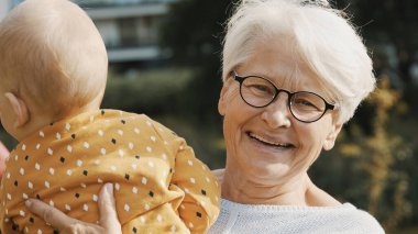 Torununu doğada kucağında tutan mutlu büyükanne.