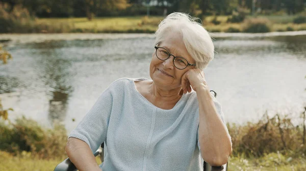 Пенсионерка в инвалидной коляске, сидящая у реки — стоковое фото