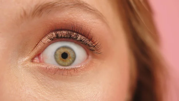 Macro shot of scared surprised green woman eye with eye shadow isolated on pink background — Stock Photo, Image