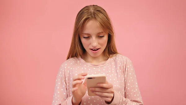 Jovem caucasiana de pijama usando smartphone, isolado em fundo rosa — Fotografia de Stock
