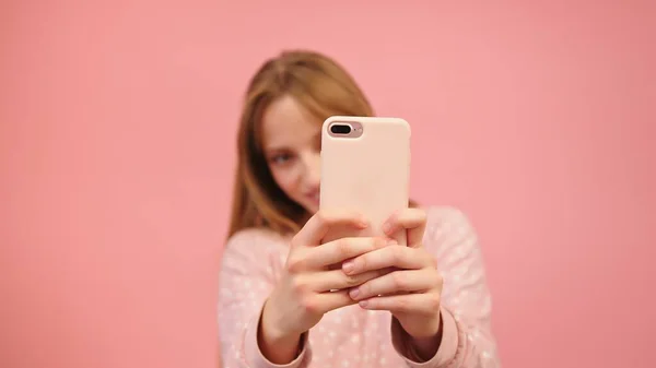 Молодая кавказка пользуется смартфоном и фотографирует. Изолированный на розовом фоне — стоковое фото