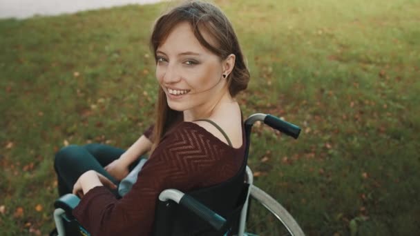 Gyönyörű fogyatékos kaukázusi nő néz a válla fölött a parkban — Stock videók