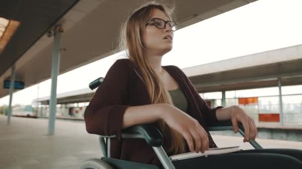 Gehandicapte jonge vrouw wachtend op een trein in de rolstoel — Stockvideo