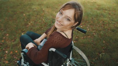 Güzel engelli beyaz kadın parkta arkasını kolluyor.