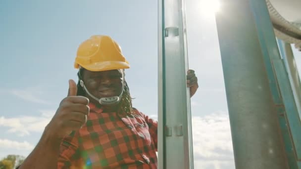 Afrikansk svart man klättrar på lederna i silio systemet med humbs upp — Stockvideo