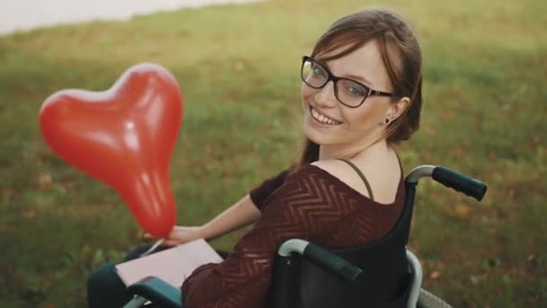 Behinderte junge Frau mit rotem Luftballon genießt Herbstbrise — Stockvideo